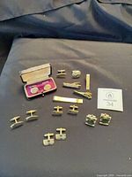 Overview of all cufflinks, tie bars and money clip on fabric background