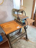 Delta scroll saw secured to wooden table on metal stand