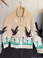 Front view of cream Cowichan sweater with duck pattern and buttons