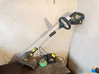 Full view of Yardworks cordless trimmer resting on table with battery, charger and line spool visible