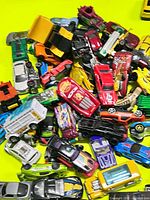 Pile of assorted Hot Wheels and other 1:64 diecast cars on yellow background