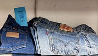 Both pairs of jeans folded side by side showing back pockets and brand patches
