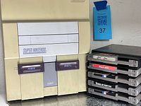 Front view of SNES console standing vertical with stack of black snap-case cartridges