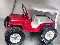 Left side view of red Tonka Jeep Dune Buggy with white roof, showcasing tires and body