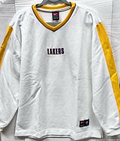 Front view of white Nike Lakers sweatshirt showing LAKERS embroidery, V-neck collar, sleeve panels, and jock tag