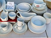 assortment of white ceramic plates, bowls, cups, gravy boat, creamer and ramekin displayed