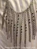 Close-up of cascading silver-tone necklace with black bead drops