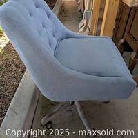 Side view of blue upholstered swivel chair on caster base