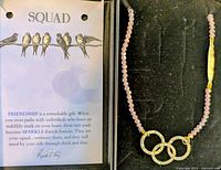 Necklace in box next to Squad message card