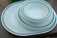 stack showing platter, plates and bowls with blue/green rim stripes