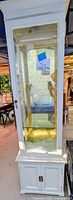 Full view of tall cream wooden cabinet with glass display top and storage base