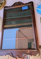 Front view of wooden spoon display cabinet with glass door and decorative carvings