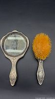 Front view of hand mirror and hairbrush showing full forms and matching design