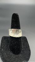 Wide hammered sterling silver band ring on ring stand