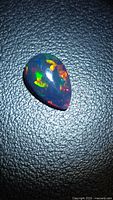 Top view of pear cabochon opal showing multicolored play of color