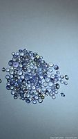 Pile of small round cut tanzanites on neutral background