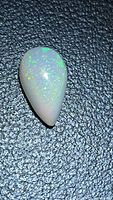Full view of pear cabochon opal showing pinfire flashes