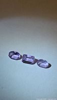 Three faceted amethyst gemstones on flat surface