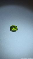 Cushion-cut green peridot under spotlight