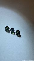 Three round blue-green sapphires arranged on white surface