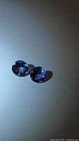 Two round violet-blue gemstones on neutral background