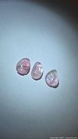 Three leaf-cut pastel pink tourmalines on neutral background