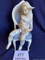 Full view of Lladro Young Harlequin figurine on chair holding cat