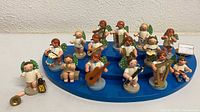 Full set of angels arranged on blue stand, extra angel and loose horn piece in foreground