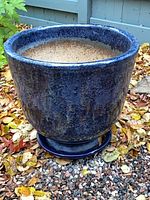 Full view of blue ceramic planter with saucer outdoors