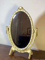 Front view of oval cream and gold tilting mirror