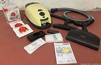 Entire lot: canister vacuum, hose, floor head, accessory nozzle, vacuum bags, manual