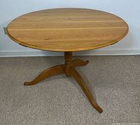 Full view of round honey oak pedestal table against wall