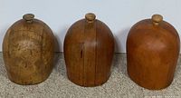 Front view of three wooden hat blocks showing overall condition and shape