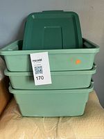 Front view of three stacked green Rubbermaid totes with lids