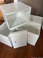 Four white wooden cubes, one upright and three tilted, showing overall look and openings