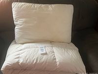 Pillow atop folded white duvet, shows overall appearance and tag