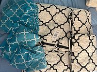 Both bedding sets laid out: blue sheet set on left, white quilted set on right