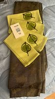 Overview of folded brown tablecloth with four green leaf-print napkins