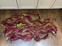 Multiple lengths of red mesh ribbon garland laid out on floor