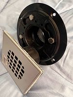 Front view of Oatey ABS shower drain showing square grate cover and threaded body