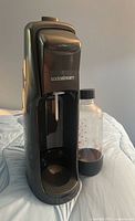 Front view of SodaStream machine beside bottle