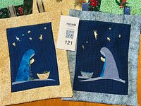 Two nativity scene quilted wall hangings with cream and blue borders
