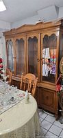 Honey oak two-piece hutch with glass doors beside table and chairs