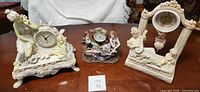 All three figurine mantel clocks on table