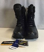 Front view of both black Bates Enforcer boots showing laces, side zipper pull tabs, Gore-Tex and Thinsulate hang tags attached.