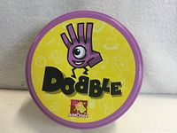 Front of purple and yellow Dobble tin