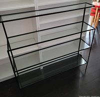 Front view showing full glass and iron shelving unit with four tiers