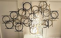 Front view of entire mixed metal wall sculpture showing interlocking circles and rods