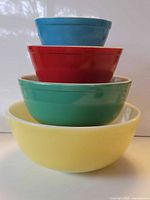 Four stacked Pyrex primary color bowls showing size gradient