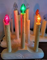 Multiple cream plastic electric candleholders lit with colored bulbs